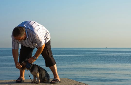 Man and his dog. Sea in the background.