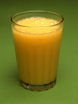 A glass of orange juice on green background
