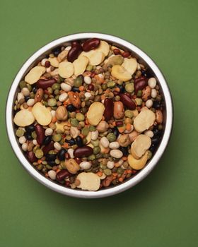 A variety of beans mixed together in a bowl on green
