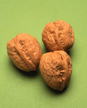 Three walnuts in the shell on green background
