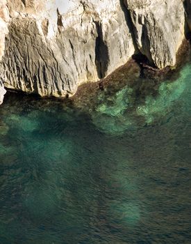 Deep clear emerald sea next to coastal cliff