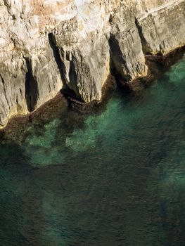 Deep clear emerald sea next to coastal cliff