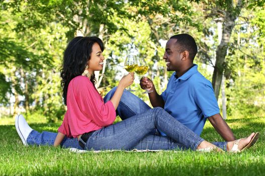 Young romantic couple celebrating with wine in summer park