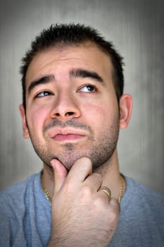 A young man with his hand on his chin thinking an important decision.