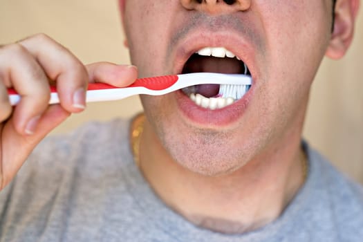 A closeup of a young man while he is brushing his teeth.