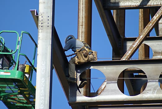 Man working on the construction of a sky scraper on a sunny day.                