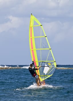 A lone windsurfer riding the waves in the Mediterranean