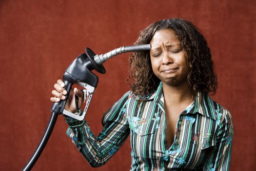 Woman holding gas nozzle like a gun to her head