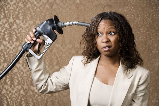 Woman holding gas nozzle like a gun to her head