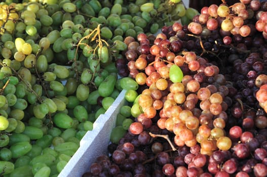 Two piles of green and red grapes at a farmer's market