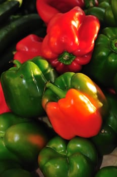 Red, green, and two-color bell peppers arranged at a farmer's market