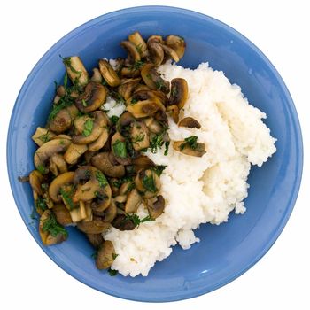 Champignons and rice on a blue plate on a white background.