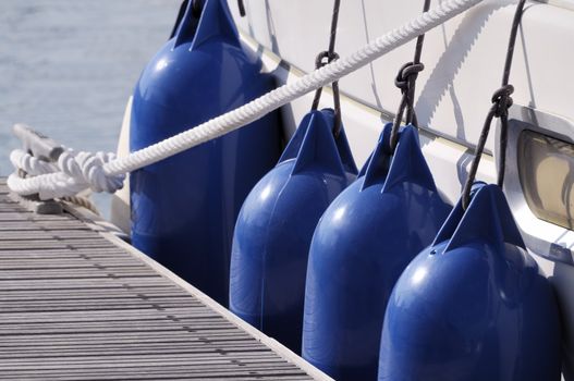 Detail of a boat secured to jetty with a rope and bumpers