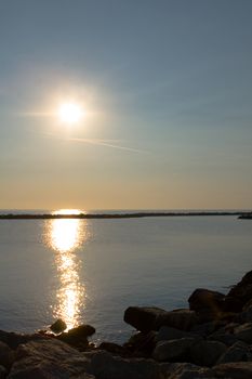 A very bright sunrise over a Mediterranean rocky seascape.