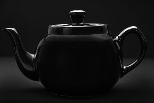 black ceramic teapot over black background