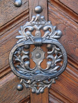Ancient doorknob on massive wooden door.