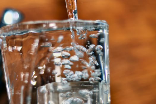 glass being filled with water and overflowing with bubbles