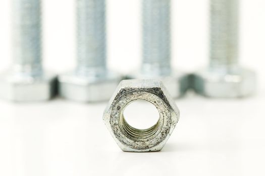 one bolt in front of four screws on white background