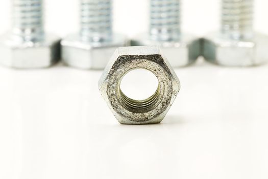 one bolt in front of four screws on white background