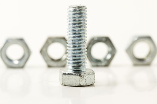 one screw standing in front of four bolts on white background