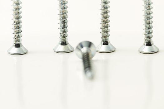 four screws standing behind one screw on white background