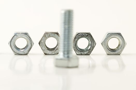 four screws standing behind one bolt on white background