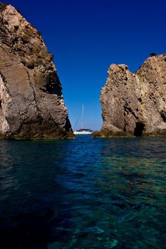 Yacht cruising between two rocks in Ponza island, Italy