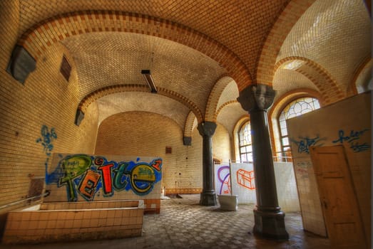 old tiled bath with graffiti on the walls