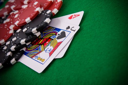 Ace of hearts and black jack with black and red poker chips in the background.