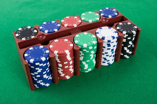 Poker chips in a box on green poker table.