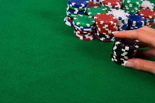 Female hand putting black poker chips into game.