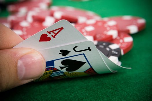 Ace of hearts and black jack with red poker chips in the background.