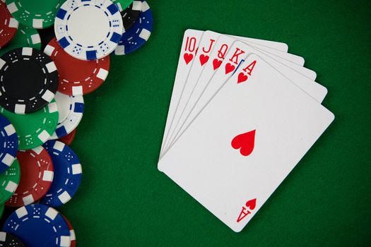 Cards with poker arrangement and poker chips on green table.