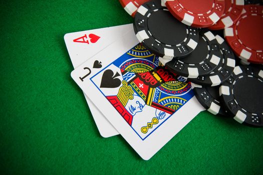 Ace of hearts and black jack with red and black poker chips in the background.