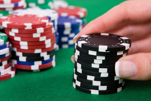 Female hand putting black poker chips into game.