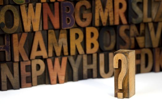 question mark against out of focus alphabet wall background - vintage letterpress wooden type stained by ink