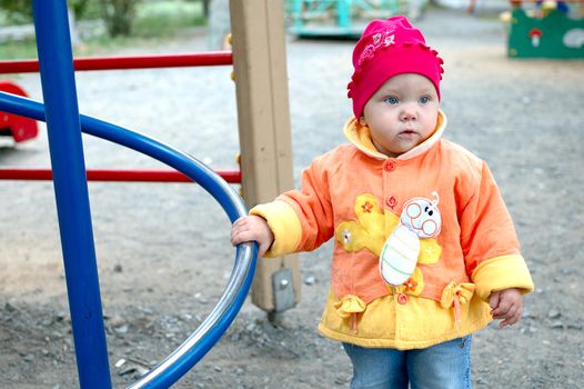 Pretty little girl stay near slide on playground.