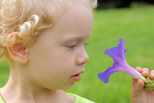 Eco friendly blondie girl staring at violet flower