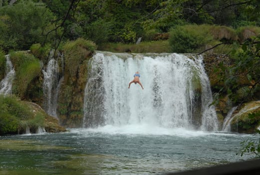 Man jumping down to wild water  
