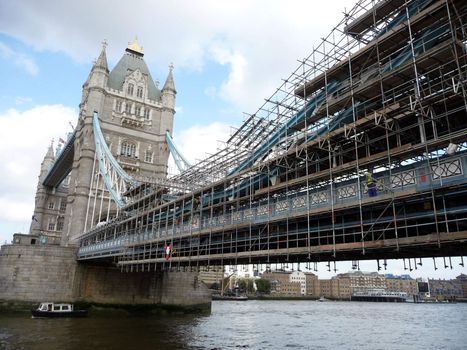 A view of the historic Tower Bridge partly covered in scaffolding, which is located over the River Thames in London.
.