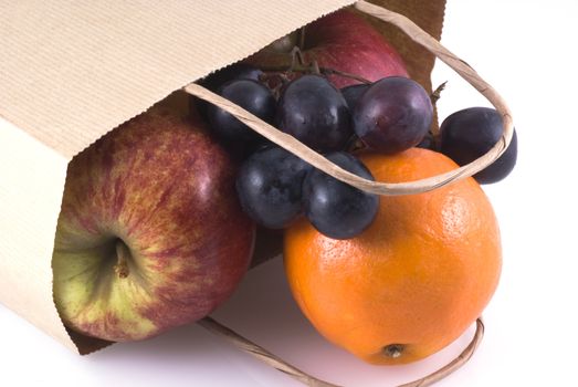 Different kinds of fruit in a paper bag on a white background.