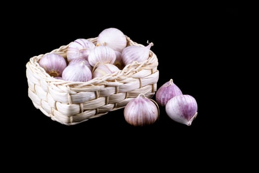 Basket full of garlic isolated on a black background.