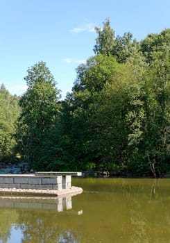 Jetty and jumping ramp over still lake surface.
