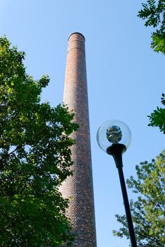 Old brick factory chimney and a glass street light.
