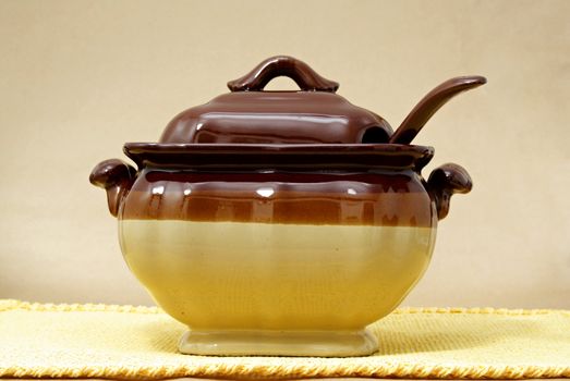 soup tureen on yellow tablecloth, beige background