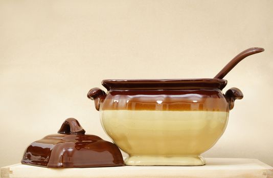 soup tureen on yellow tablecloth, beige background