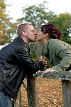 A young happy couple passionately kissing each other outdoors in the fall.