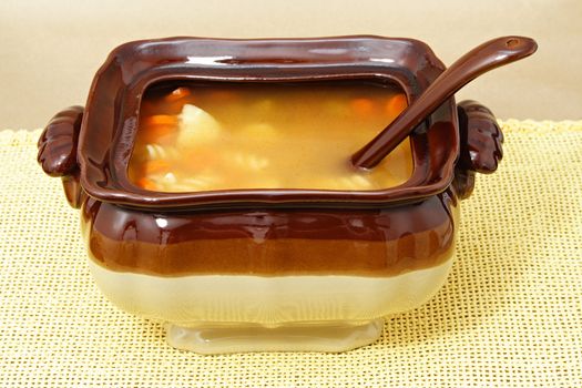 soup tureen on yellow tablecloth, beige background