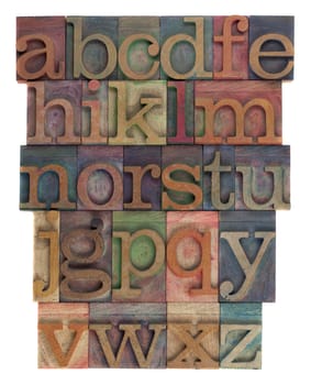 English alphabet (lower case) in vintage wooden letterpress type, stained by  inks of different colors, flipped horizontally, isolated on white