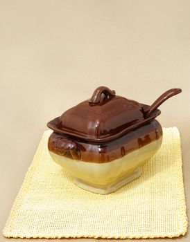 soup tureen on yellow tablecloth, beige background